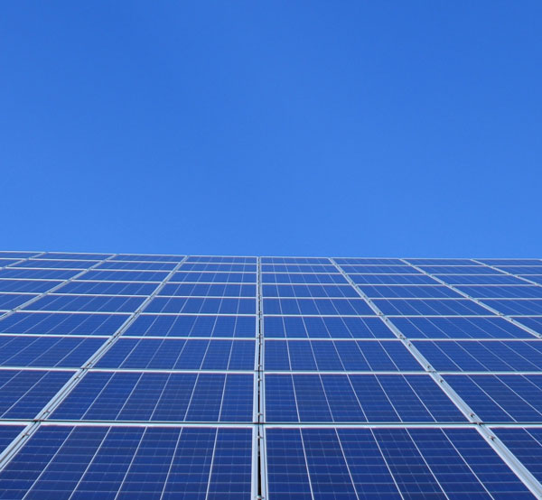 Solarpanele auf einer Dachfläche vor blauem Himmel, erzeugen Strom aus Sonnenlicht